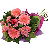 Freshly wrapped bouquet of pink flowers · including gerberas, alstroemerias, carnations and a single pink rose.