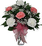 Pretty floral arrangement in a glass vase of one half dozen white and pink carnations with baby's breath, greenery and pink organza bow.