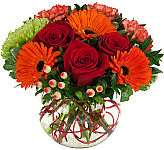 Luxurious arrangement of roses, Gerbera, carnations and spider mum in a clear glass bowl with decorative treatments.