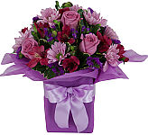 Lavender roses and daises are arranged with pink alstroemeria and purple statice in a lavender tissuewrapped bouquet.