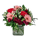 Lovely glass cube vase flower arrangement of pink, peach, purple and white blooms for birthday gift giving.