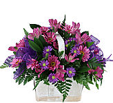 A pretty handled basket is florist arranged with inspiring pink, purple, lavender and burgundy flowers.