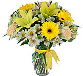 Pretty arrangement of fresh flowers in a glass vase in a sunny yellow and white colour theme.