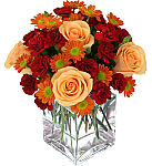 A modern glass cube vase is arranged with Autumn hued flowers, including roses, mums and carnations. Same day flower delivery in Canada.