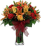 Our premier Fall flower arrangement featuring yellow and orange roses, orange lilies, red carnations and hypericum berries, ample lush greenery and red organza bow.