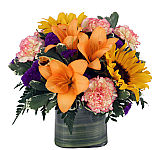 Leaf lined cube vase with sunflowers, lilies, and more.