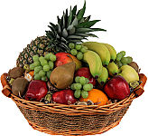 A variety of fresh fruit from North America and other parts of the world is arranged in a wicker basket.