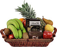 A handled wicker basket is filled with popular, fresh assorted fruit plus some delicous chocolates.