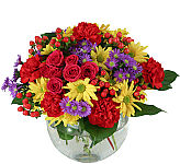 Glass bowl flower arrangement of pink roses, red carnations, purple asters and yellow daisy mums