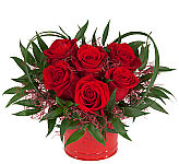 Unique and expressive rose arrangement designed in the shape of a heart with artistic greenery and red vase.