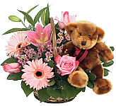 Handled wicker basket arranged with pink lilies, Gerbera, roses and wax flowers plus a plush brown teddy bear · for Maternity gift giving in Canada.