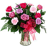 A pretty floral arrangement of six pink and lavender roses with six variegated carnations in pink and coral hues.