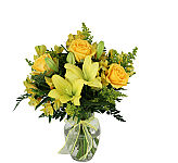 Yellow lilies, roses, alstroemeria and statice are arranged in a clear glass vase with matching yellow bow.