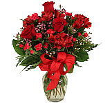 Romantic floral arrangement of red roses, red alstroemeria, magenta carnations and pink waxflower for Valentine's Day.