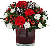 A charming red vase of red and white flowers with added ornamental glass balls and frosted pinecones.