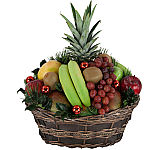 Assorted fresh fruit basket with added sprigs of holly and Christmas greens, along with red ornamental balls for the Holidays.