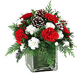 A delightful, affordable flower arrangement of red and white blooms in a modern red glass cube vase with all the Christmas trim.