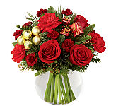 Clear glass bowl of red roses, red carnations, burguny miniature carnations and holiday greenery with added golden ornamenal ball pics and more.