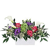 A white ceramic container of calla lilies roses and more.