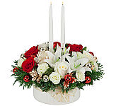 A white and red floral centerpiece for Christmas with abundant flowers, including red roses, white roses, lilies and more · including two taper candles.