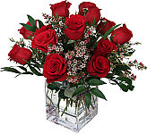A modern cube vase is arranged with one dozen premium red roses and lovely pink waxflower.
