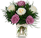 Elegant floral design of 1/2 dozen lavender and cream roses in a glass cube vase with greens and matching bow.