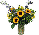A flared glass vase expertly arranged with sunflowers, roses, lilies, and more!