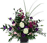Pretty floral arrangement in a vase featuring stargazer lilies, yellow Gerbera daisies and more for sympathy.