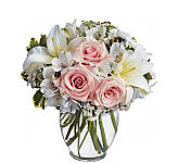 A glass vase holds light pink roses with white lilies, white alstroemeria, statice and greenery. Available for same day delivery.