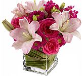 Stellar floral arrangement of hot pink roses with pale pink lilies and mixed blossoms, arranged in a sparkling, modern glass cube vase. We are Canada Flowers.