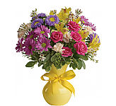 Upbeat floral arrangement of assorted blooms in a yellow vase tied with yellow polka dot ribbon.