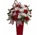 Give the gift of peppermint joy with a tall Christmas arrangement that s graphic, bold and stylish! Red carnations mingle with white blossoms and evergreens in this chic bouquet that s decorated with candy canes and a fancy red and white striped ribbon.