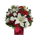 A red glass cube vase is arranged with red spray roses, red carnations, white lilies, white mini carnations, hollay and holiday greenery.