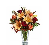 Beautiful Teleflora Fall vase arrangement of orange lilies, orange and red roses, millet and oak leaves. Same day delivery available across Canada with Canada Flowers.