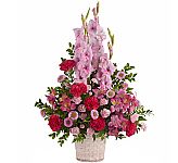 A pretty mix of fresh blossoms and blooms in pink tones, arranged in a white basket · designed for the funeral service.