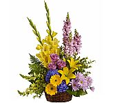 Love's Tapestry is a generous, colourful arrangement of flowers in a natural wicker basket to express sympathy at a funeral service.