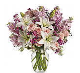 This lovely bouquet includes light pink spray roses, white asiatic lilies, lavender stock and lavender waxflower accented with assorted greenery. Delivered in a glass rose vase.