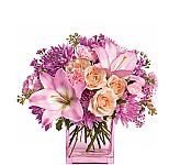 A modern pink vase is arranged with lovely flowers in various shades of pink, mauve, peach and lavender.