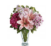A glass vase arrangement of pink flowers featuring lilies, hydrangea, alstroemeria, stock and carnations. Lovely.